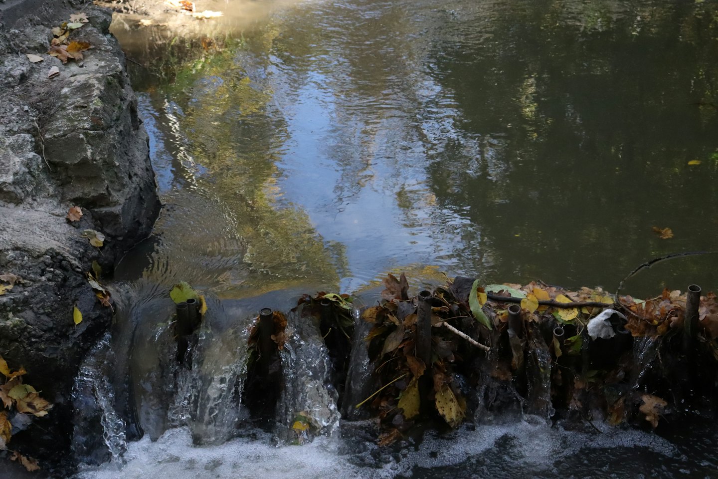 Water cascades over a concrete and metal debris dam.